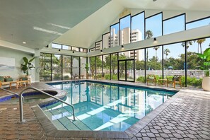 An indoor swimming pool with clear glass walls, a tiled floor, and a view of palm trees and buildings outside. - Orlando Family Resort - 2 Miles to Universal! (Orlando)