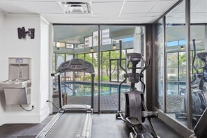 A gym with exercise equipment, a water dispenser, and a view of a pool through large windows. - Orlando Family Resort - 2 Miles to Universal! (Orlando)