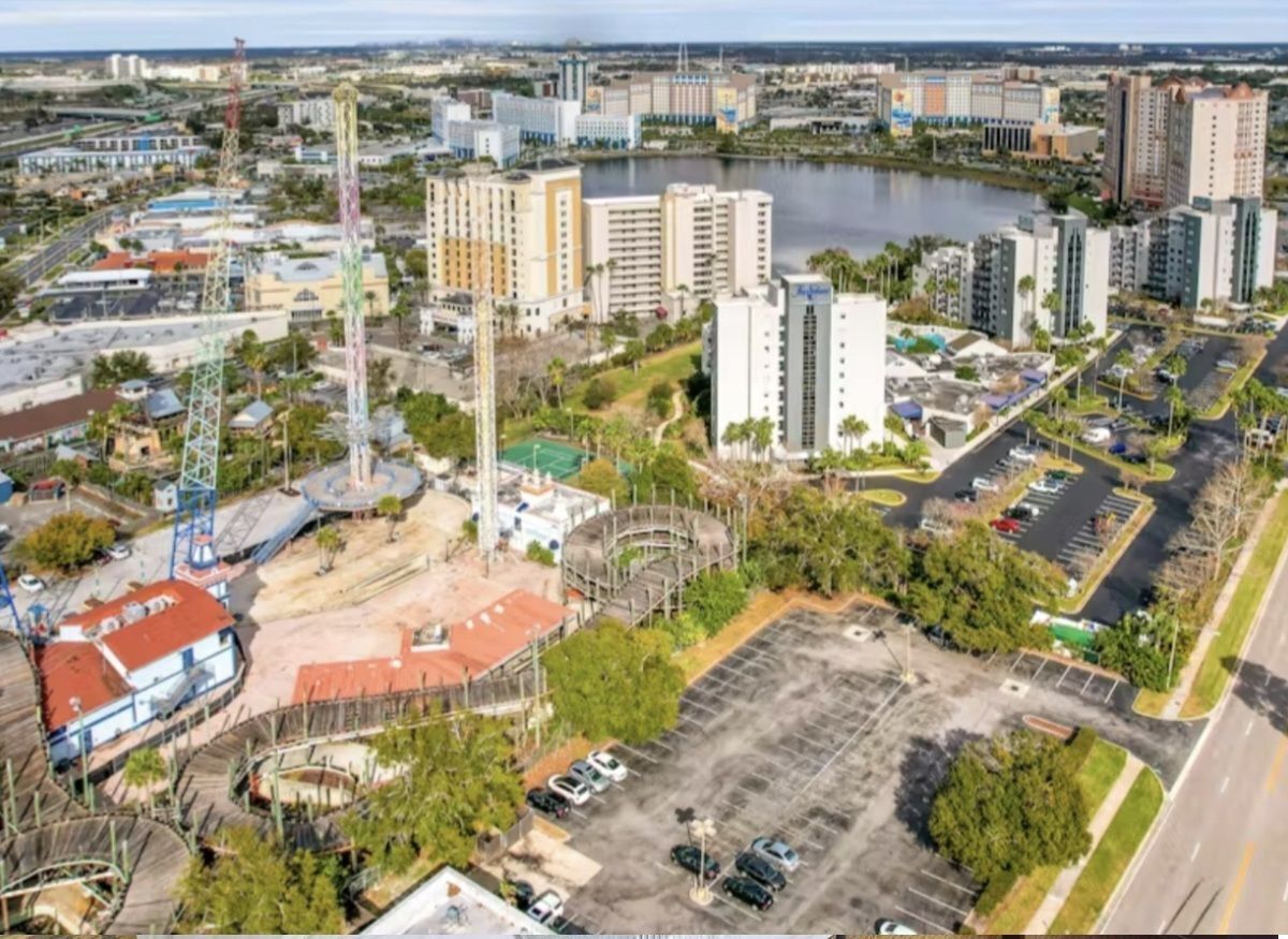 An aerial view of a cityscape with high-rise buildings, a marina, and a parking lot.