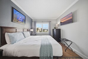 A hotel room with a bed, a desk, a chair, a TV, and a window with a view of buildings. - Orlando Family Resort - 2 Miles to Universal! (Orlando)