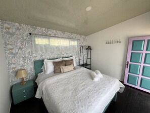Ein Schlafzimmer mit einem Bett, einem Nachttisch, einem Hängekorbstuhl und einer Tür.