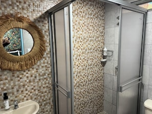 A bathroom with a tiled mosaic wall, a mirror with a decorative frame, a sink, and a shower enclosure. - CASA FINCA EN SALENTO | MIRADOR | NATURALEZA Y CALMA  | 8 HABITACIONES (Salento)