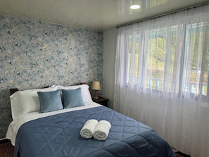 A bedroom with a bed, pillows, a nightstand, a lamp, and a window with sheer curtains. - CASA FINCA EN SALENTO | MIRADOR | NATURALEZA Y CALMA  | 8 HABITACIONES (Salento)