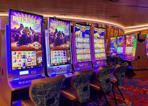 A row of slot machines with a 'Buffalo' theme, multiple screens, and a carpeted floor. - Cozy Hardrock Retreat- Walk to Hardrock Casino! Close drive Beach and Restaurant (Hollywood)