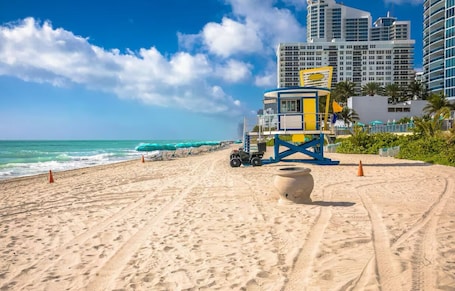 A beach with a lifeguard tower, a sandy path, and a building in the background.. Cozy Hardrock Retreat- Walk to Hardrock Casino! Close drive Beach and Restaurant