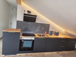 A modern kitchen with a built-in oven, a sink, and a coffee maker. - Cozy 3-bedroom vacation apartment with a private terrace and views of the mountains and lake (Hergensweiler)