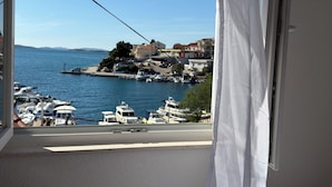 A room with a view of a marina, boats, and buildings across the water. - Apartment right by the sea - 2 balconies, sea view of Krapanj (Brodarica)