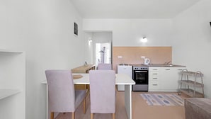 A compact kitchen with a stove, oven, and sink. There is a dining area with a table and chairs. - Apartment right by the sea - 2 balconies, sea view of Krapanj (Brodarica)