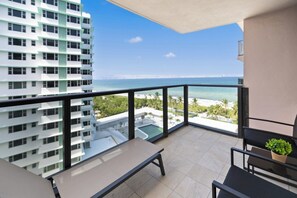 Ein Balkon mit Meerblick, ein Schwimmbad und ein Hochhaus.