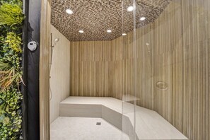 Een moderne douche met een geruit plafond, verticale houten lambrisering en een glazen scheidingswand.