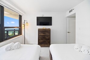 Een hotelkamer met twee bedden, een televisie, een houten dressoir en een raam met uitzicht.