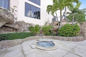 A hot tub surrounded by rock formations and greenery, with a building in the background. - Spacious Ocean View Condo w/Resort Amenities 1108 (Miami Beach)
