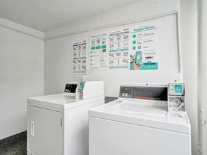 A laundry area with two washing machines, a dryer, and instructional posters on the wall. - Spacious Ocean View Condo w/Resort Amenities 1108 (Miami Beach)