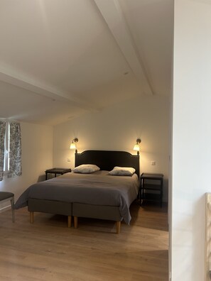 Ein Schlafzimmer mit Bett, Nachttischen und einem Fenster mit Vorhängen.