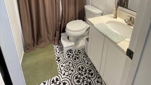 Kylpyhuone, jossa on wc, pesuallas ja suihkuverho.