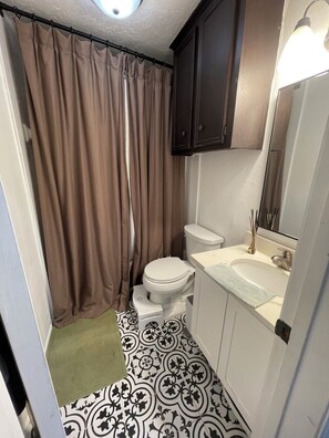 Un baño con inodoro, lavamanos y cortina de ducha.