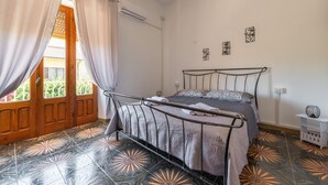Ein Schlafzimmer mit Bett, Vorhängen, einer Tür und einem Fliesenboden.