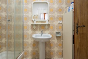 A bathroom with a shower, a sink, a mirror, and a toilet. - Domus Mario – Spacious Apartment in the Heart of Sant’Antioco (Sant'Antioco)