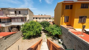 Ein Wohngebiet mit einer Treppe, die zu einem Balkon führt, umgeben von Gebäuden und Grünflächen.