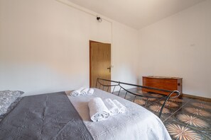 Ein Schlafzimmer mit einem Bett, einer Holztür, einer kleinen Holzkommode und einem Stuhl.