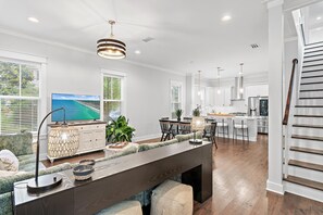 A modern kitchen with a dining area, large windows, and a view of the ocean. - The Greenhouse (Santa Rosa Beach)