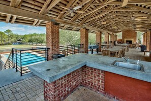 An outdoor patio area with a pool, a barbecue grill, and a seating area. - The Greenhouse (Santa Rosa Beach)