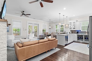 A spacious living area with a brown leather sofa, a white couch, and a dining area with a table and chairs. - Jaybird Bungalow (Santa Rosa Beach)