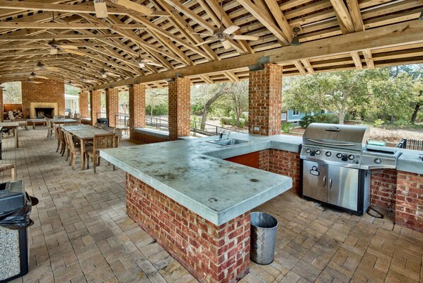 An outdoor kitchen with a brick island, a grill, and a ceiling fan. - Jaybird Bungalow (Santa Rosa Beach)