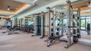 A gym with various exercise machines, mirrors, and a carpeted floor. - Beautiful luxury high-rise condo with views of downtown Los Angeles in Koreatown (Vernon)
