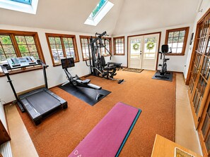 A home gym with exercise equipment, large windows, and a view of the outdoors.
