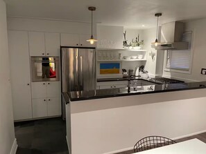 Una cocina moderna con electrodomésticos de acero inoxidable, una encimera negra e iluminación colgante.