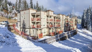 Ein mehrstöckiges Hotel mit Balkonen, einer verschneiten Landschaft und einem Parkplatz.