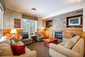 Ein Wohnzimmer mit Kamin, Fernseher und einer Steinwand.