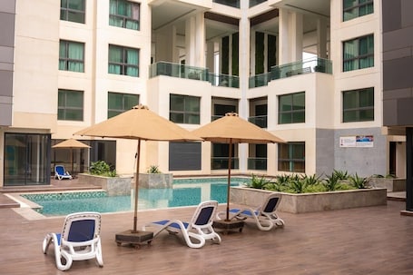 A hotel courtyard with a swimming pool, lounge chairs, and umbrellas.. FITINI APARTMENT