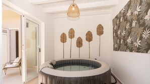 Ett spa-rum med ett träbadkar, en glasdörr som leder ut till en balkong och en väggdekoration i form av löv.