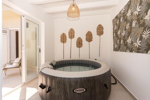 A spa room with a wooden hot tub, a glass door leading to a balcony, and a wall-mounted leaf decoration. - Villa Harem - Santa Maria Del Fo... (Santa maria del focallo)