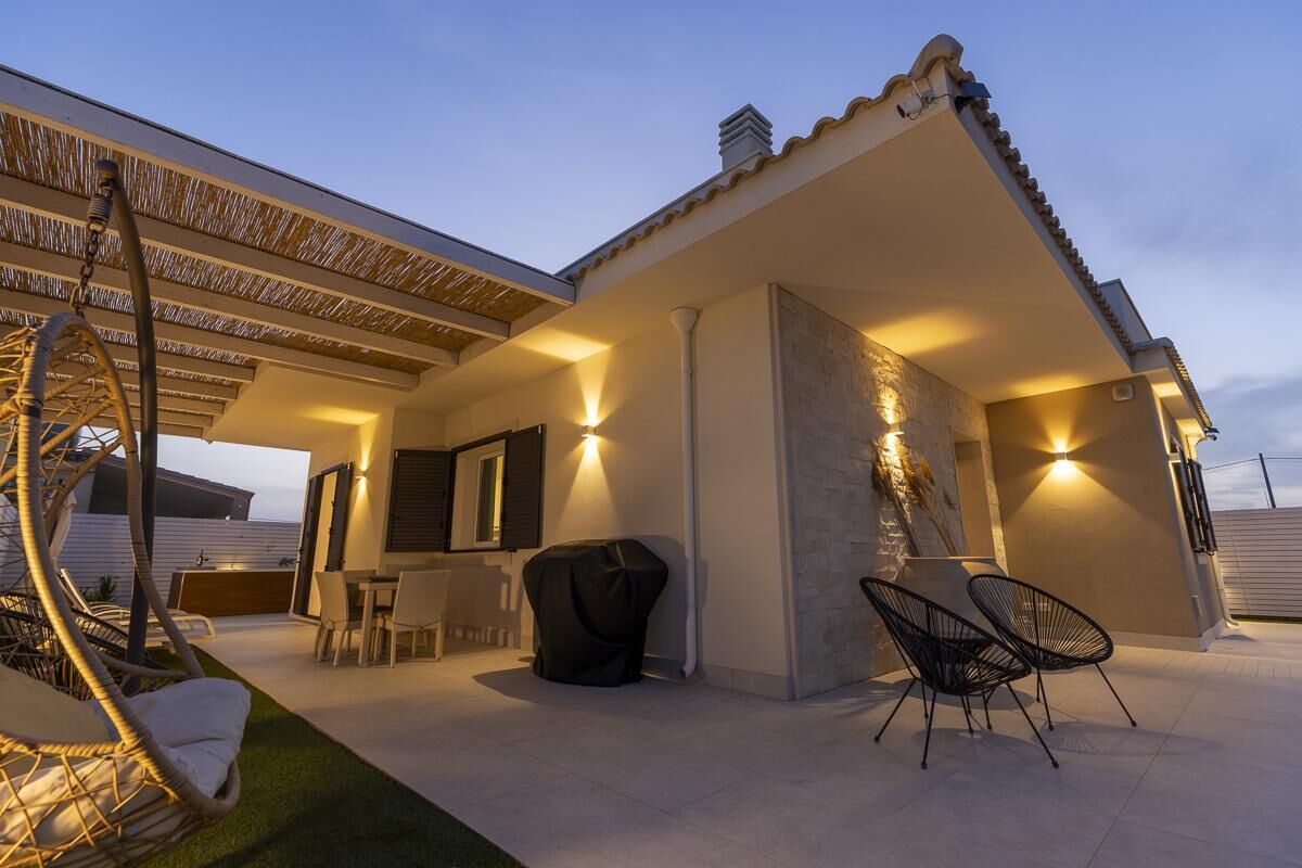 A covered outdoor area with a dining table, chairs, and a swing chair.