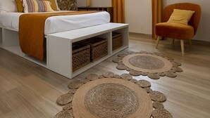 Una camera da letto moderna con un letto, un comodino, una sedia, una lampada a sospensione e una finestra con tende.