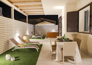 Un espacio al aire libre techado con mesa de comedor, sillas y sillones.