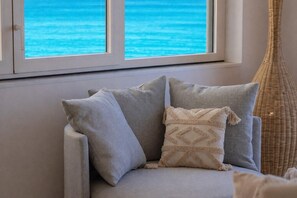 Ein Sofa mit Kissen und Blick auf das Meer durch ein Fenster.