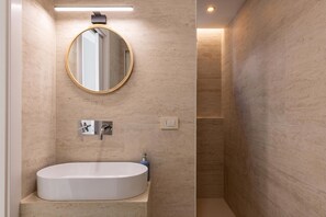 Ein modernes Badezimmer mit einer freistehenden Badewanne, einem runden Spiegel und einem wandmontierten Wasserhahn.