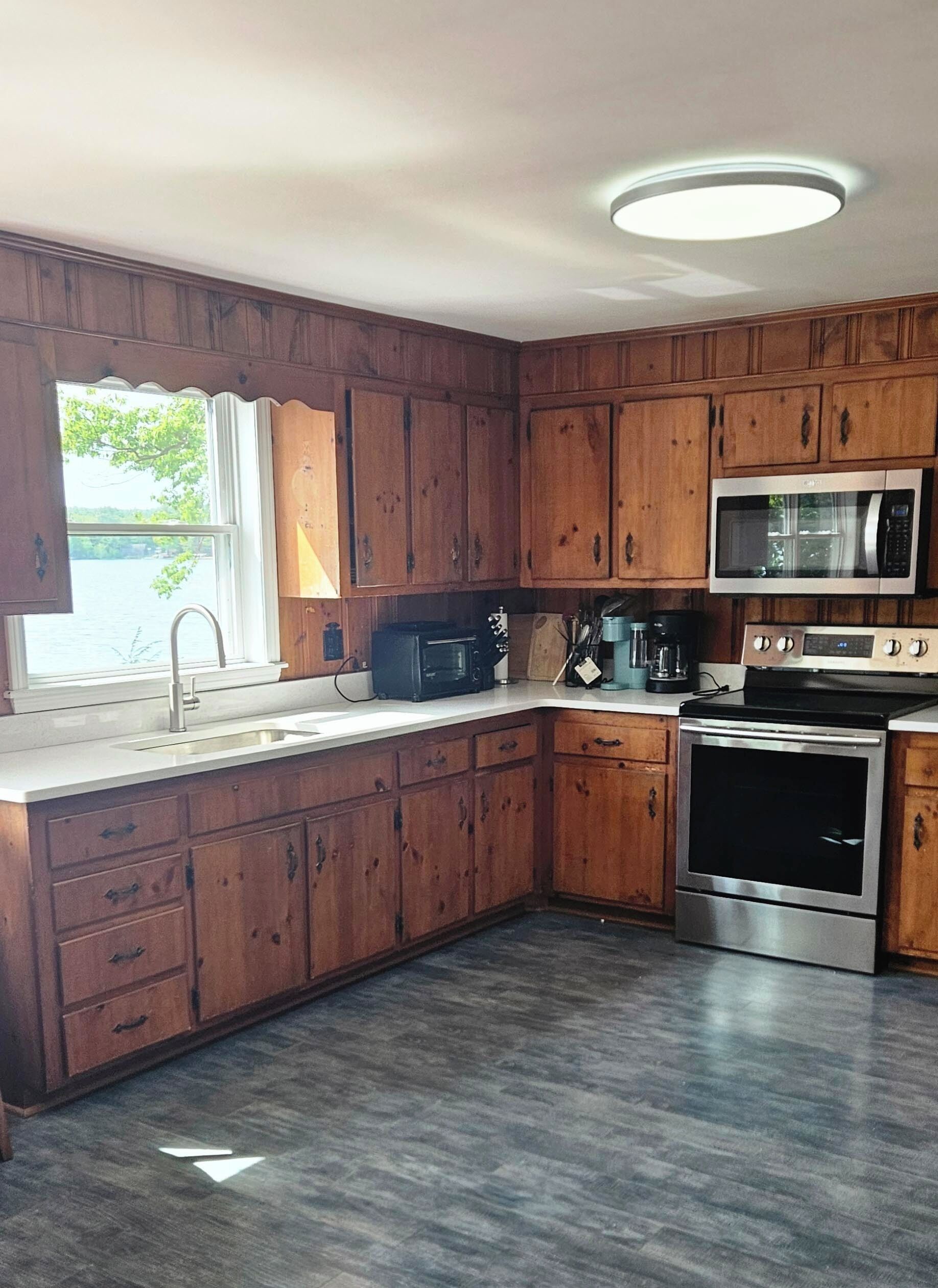 A kitchen with wooden cabinets, a stainless steel microwave, and an oven.