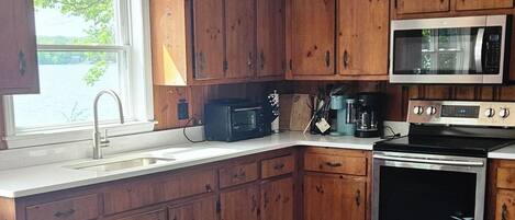 A kitchen with wooden cabinets, a stainless steel microwave, and an oven.