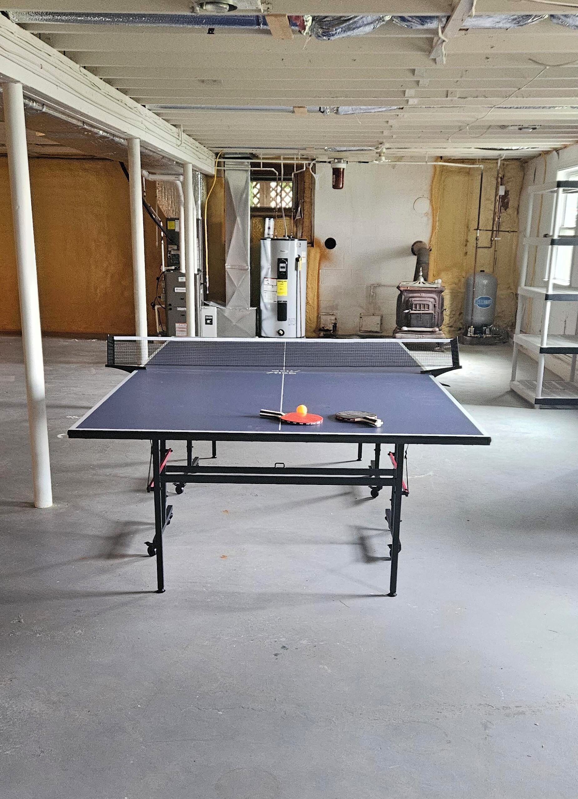 Een pingpongtafel in een ruime kamer, uitgevoerd in industriële stijl, met open plafonds en zichtbare ventilatiekanalen.