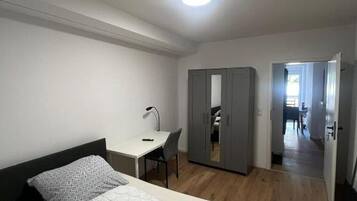 A bedroom with a bed, a desk, and a wardrobe.