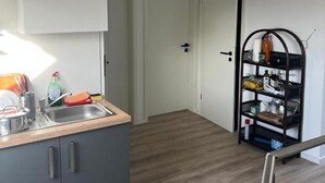Moderni keittiö, jossa on integroitu pesuallas, pieni keittiösaareke ja metallinen hylly, jossa on erilaisia esineitä.