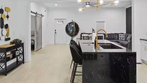 Een moderne keuken met een zwart marmeren kookeiland, een zwart-wit bank en een plafondlamp.