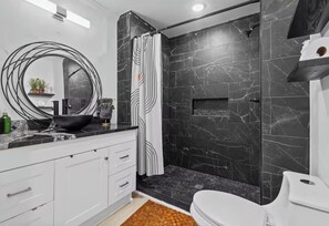 Une salle de bain moderne équipée d’une douche, de toilettes et d’un grand miroir.