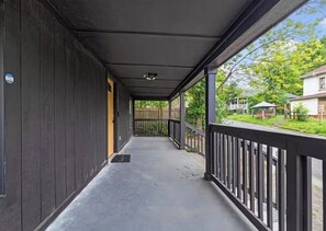 A covered porch with a metal railing, a door on the left, and a view of a residential street. - Spacious Home - Near Duke Hospital, Downtown Durham & RTP (Durham)