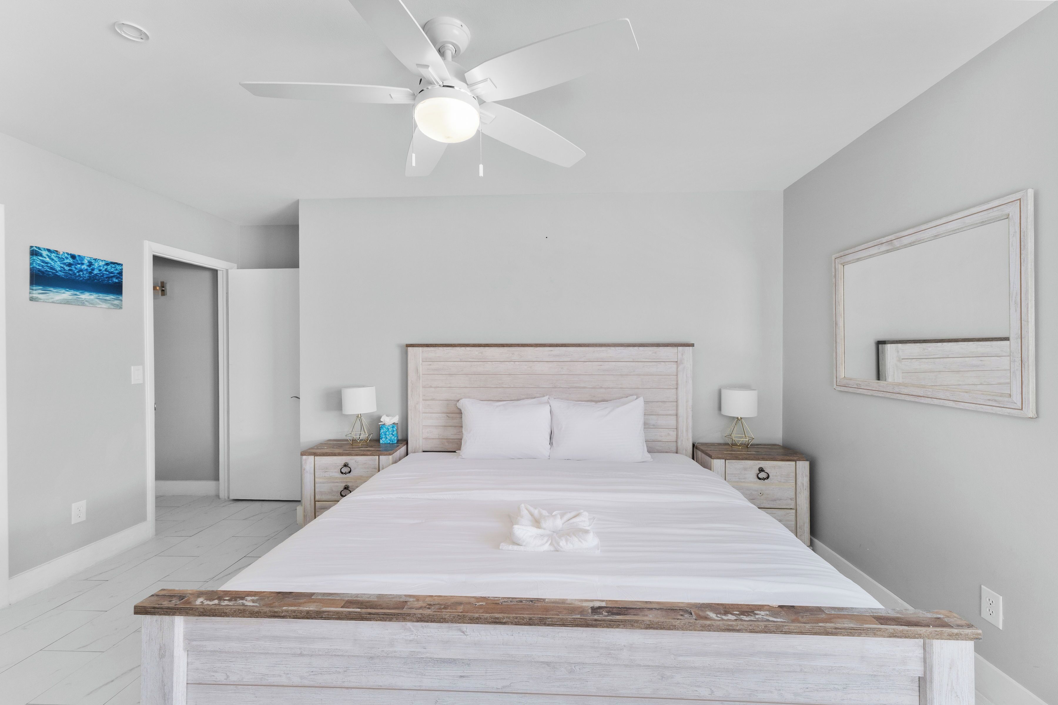 A bedroom with a bed, a ceiling fan, bedside tables, and a nightstand.